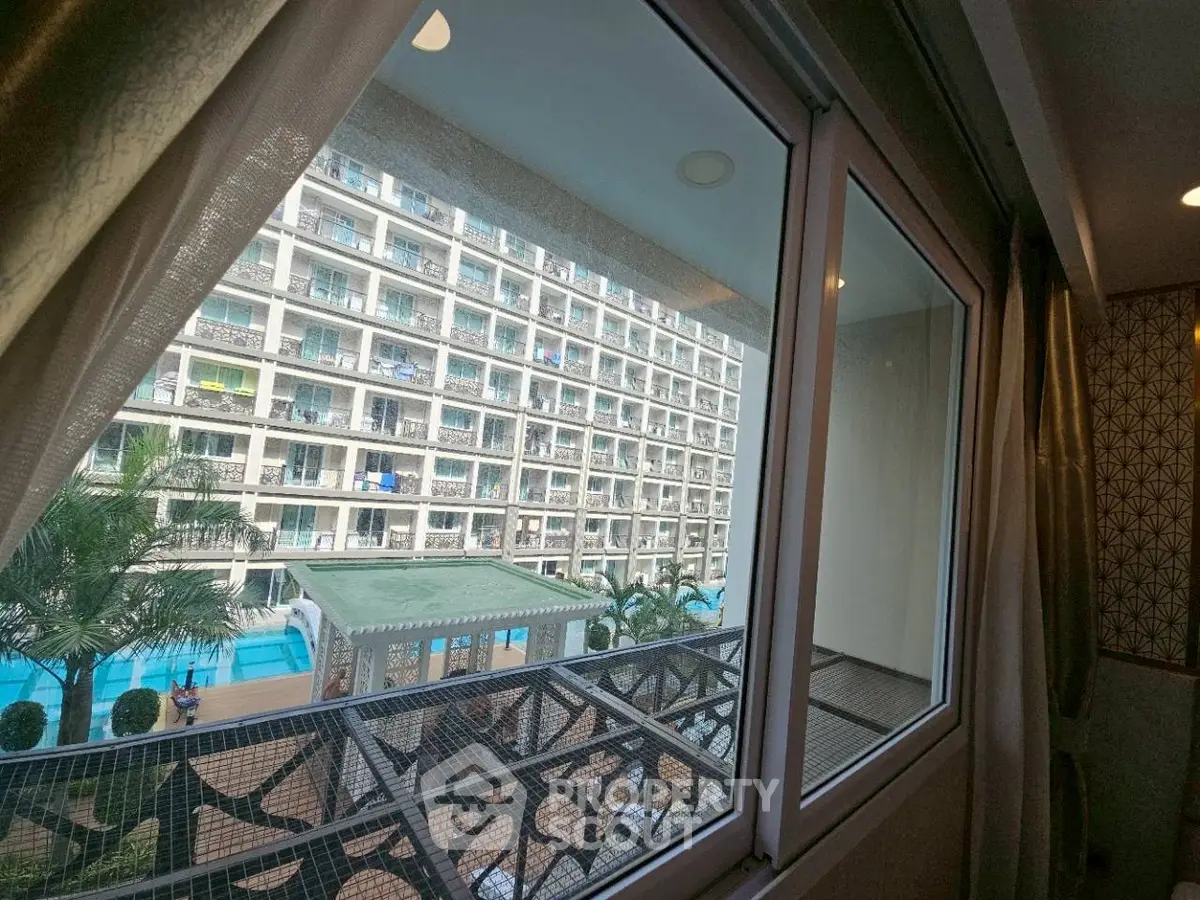 Stunning view from apartment window overlooking modern building and pool area, perfect for urban living.