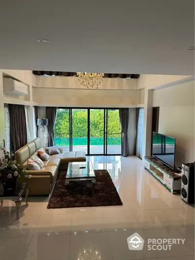 Luxurious living room with glossy marble flooring, elegant leather sofa set, and floor-to-ceiling windows overlooking a lush garden. Features a sophisticated chandelier and modern entertainment system.