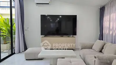 Modern living room with large TV, cozy sofa, and elegant decor.