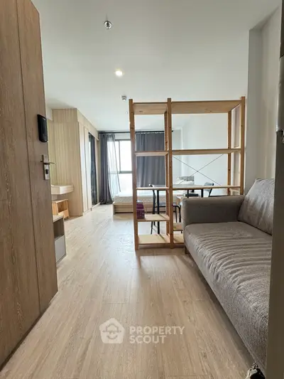 Modern open-plan apartment with wooden flooring and stylish furniture, featuring a cozy living area and natural light.