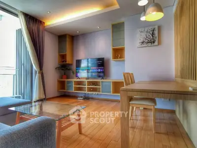 Modern living room with stylish decor, wooden flooring, and a large TV, perfect for relaxation and entertainment.