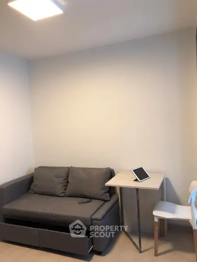 Cozy living room with modern sofa and tablet on table, ideal for compact living spaces.