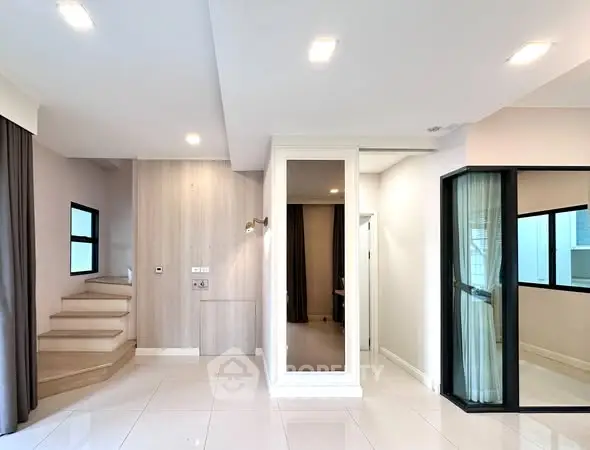 Modern interior with sleek staircase and glass partition in a bright, open space.