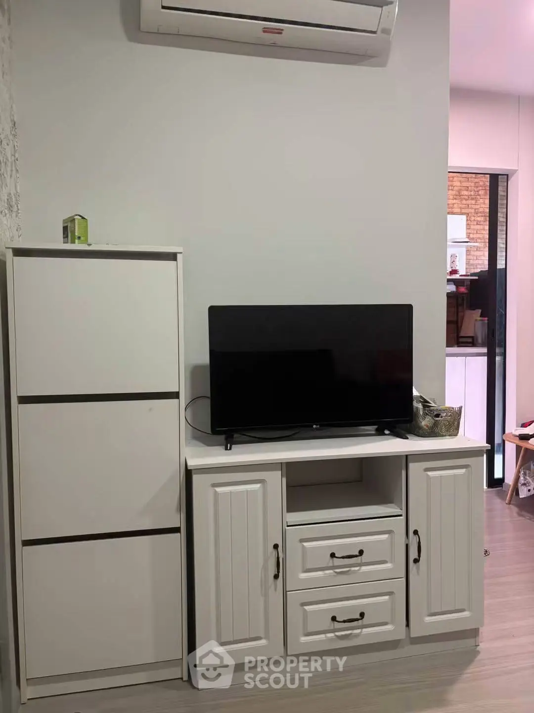 Modern living room with sleek white furniture and wall-mounted air conditioner
