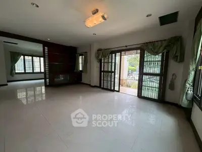 Spacious living room with large windows and elegant curtains, perfect for natural light and comfort.
