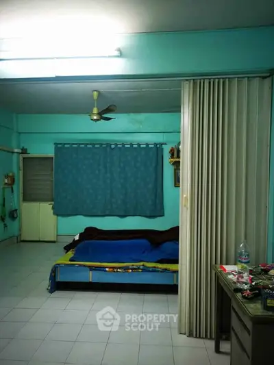 Spacious bedroom with blue walls and a ceiling fan, featuring a bed and a sliding partition.