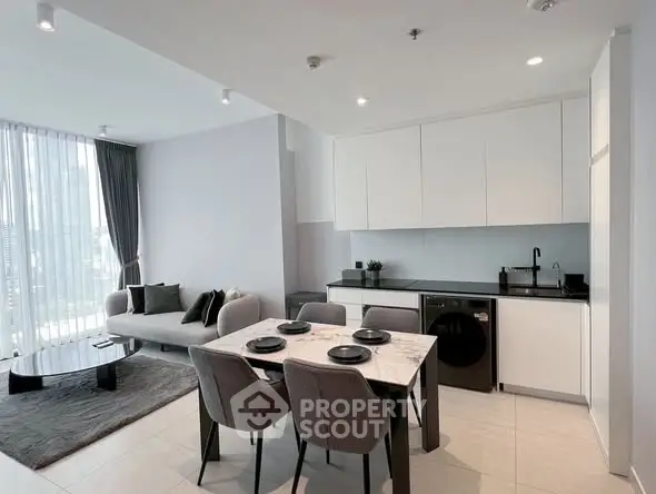 Modern open-plan living room and kitchen with sleek furnishings and natural light.