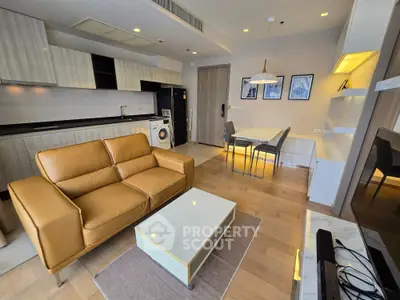 Modern living room with open kitchen, featuring leather sofa and dining area in stylish apartment.