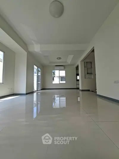 Spacious modern living room with large windows and glossy tiled floors