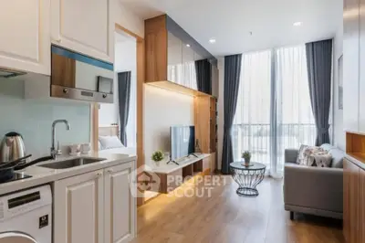 Modern open-plan living room with kitchen, featuring sleek design and natural light.