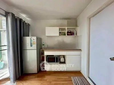 Modern kitchen with fridge, microwave, and open shelving in a bright apartment.