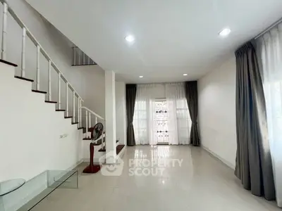 Spacious living room with elegant staircase and large windows