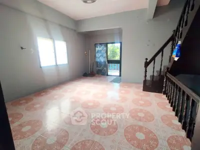 Spacious living room with patterned tile flooring and staircase, ideal for family gatherings.