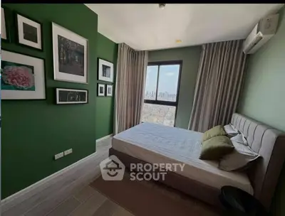 Stylish bedroom with city view, green accent wall, and modern decor in a high-rise apartment.