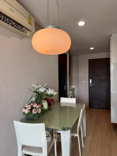Modern dining area with elegant lighting and floral centerpiece in a stylish apartment.