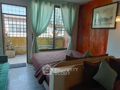 Cozy bedroom with large windows and vibrant decor, offering a comfortable and inviting atmosphere.