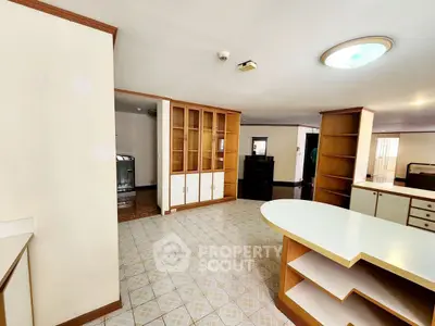 Spacious open-plan living area with built-in wooden shelves and tiled flooring