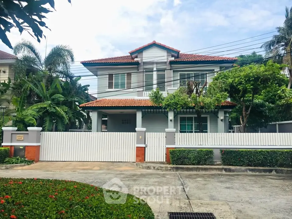 Charming two-story house with red-tiled roof and lush garden in a serene neighborhood.