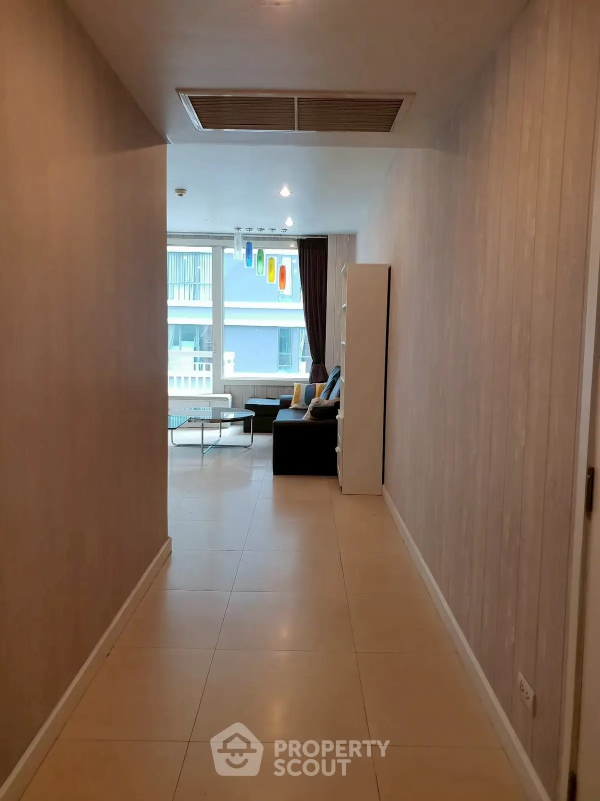 Spacious hallway leading to a modern living room with large windows and stylish decor.