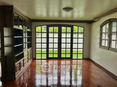 Spacious living room with elegant wooden flooring and large windows overlooking a lush garden.