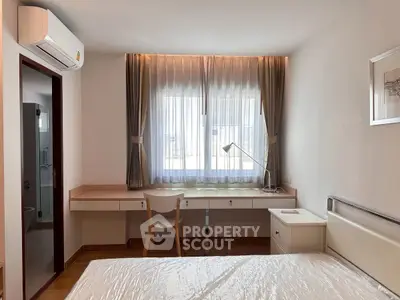 Bright bedroom with modern furnishings and natural light through large window.
