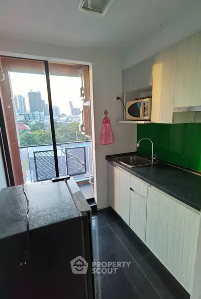 Modern kitchen with city view, featuring sleek cabinetry and large window for natural light.