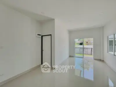 Spacious modern living room with large windows and glossy floors in a bright, minimalist home.