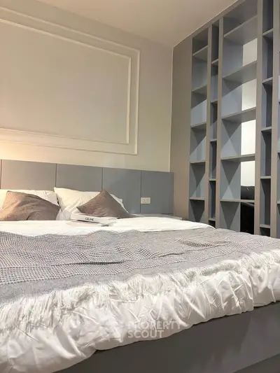 Modern bedroom with stylish shelving and cozy bedding in a contemporary apartment.