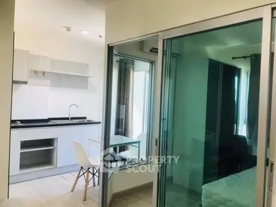 Modern apartment with open kitchen and glass partitioned bedroom, ideal for urban living.