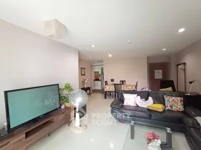 Spacious living room with modern decor and ample natural light, featuring a cozy seating area and entertainment setup.