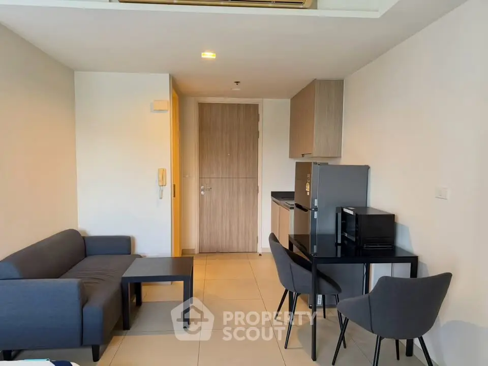 Modern living room with sleek furniture and compact kitchen area in a stylish apartment.