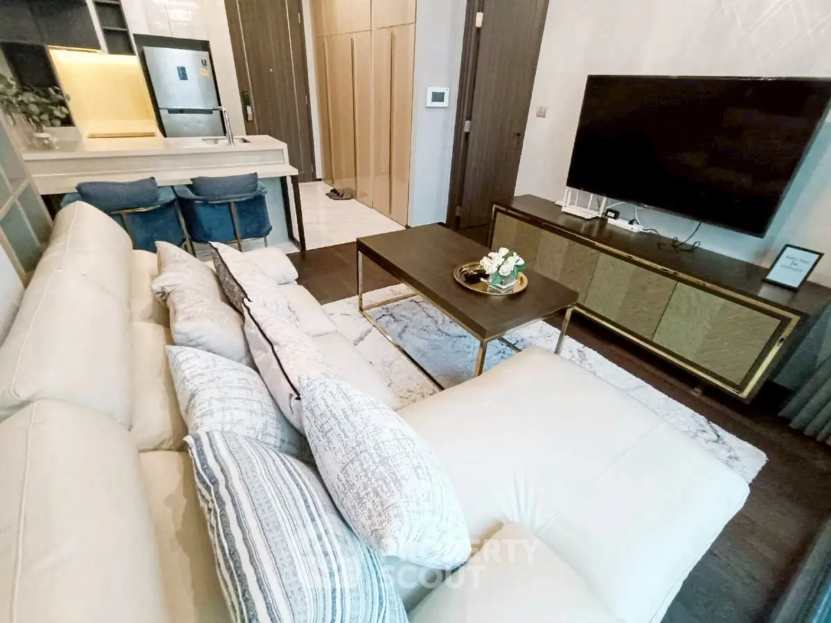 Modern living room with plush white sofa, sleek TV unit, and stylish kitchen area.