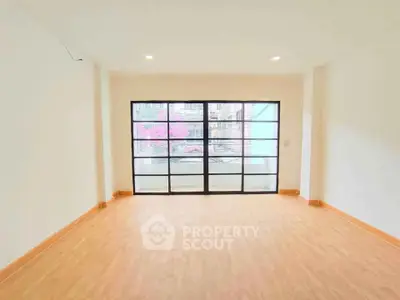 Spacious empty room with large windows and wooden flooring