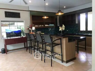 Spacious kitchen with island and bar stools, featuring open layout and modern lighting.
