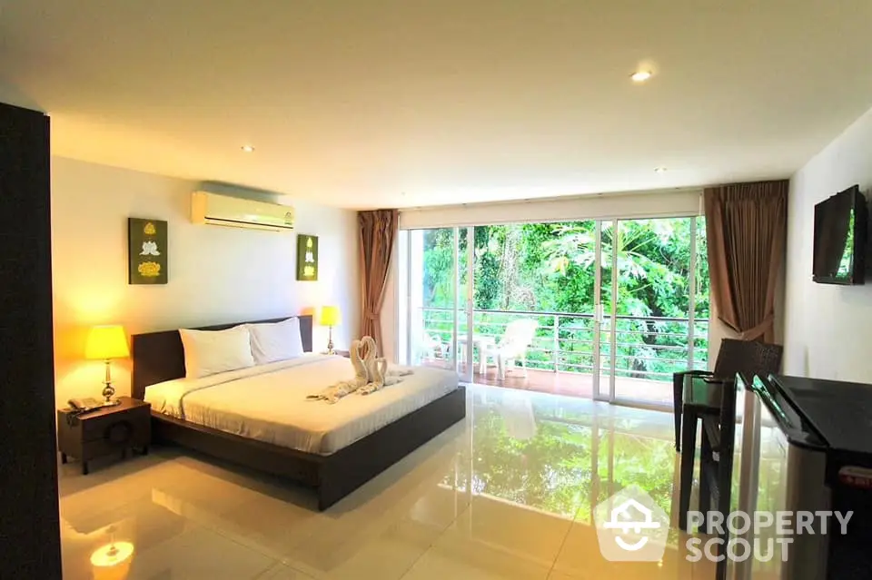 Spacious bedroom with large windows and lush garden view, featuring modern decor and natural light.