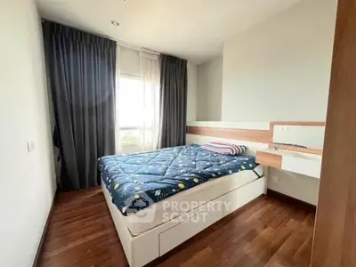 Cozy bedroom with wooden flooring and large window for natural light