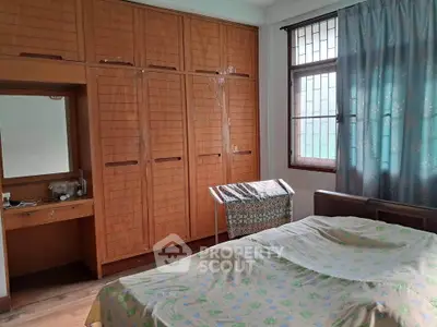 Cozy bedroom with wooden wardrobe and large window for natural light