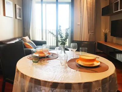 Charming living room with dining area, elegant decor, and natural light from large windows.