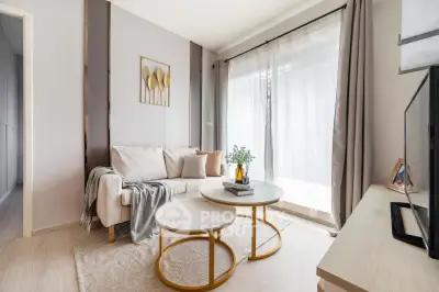 Modern living room with cozy sofa, stylish decor, and natural light through large windows.