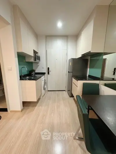 Modern kitchen with sleek cabinetry, washing machine, and dining area in a compact apartment.