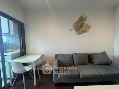 Modern living room with gray sofa and dining area, featuring stylish wall decor and natural light.
