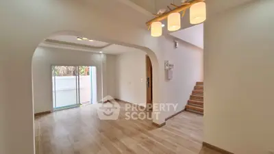 Spacious modern living room with wooden flooring and stylish lighting, perfect for family gatherings.