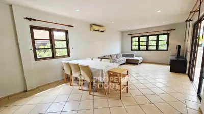 Spacious living room with dining area and large windows offering natural light.