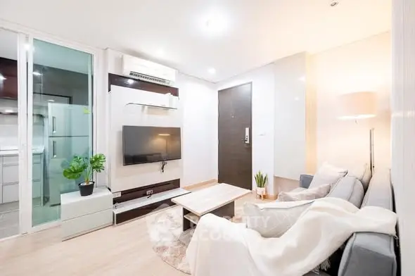 Modern living room with sleek furniture and wall-mounted TV in a cozy apartment.