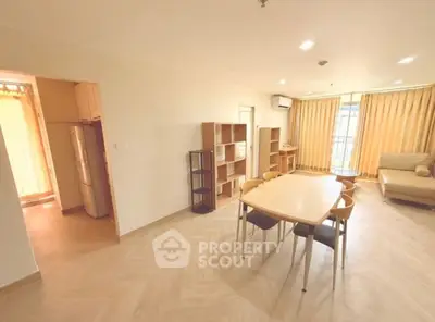 Spacious living room with dining area and balcony access in modern apartment.