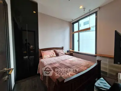 Cozy bedroom with modern decor and large window offering natural light.