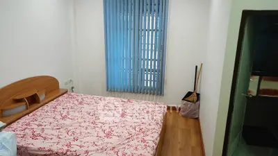Cozy bedroom with wooden flooring and floral bedspread, featuring vertical blinds on the window.