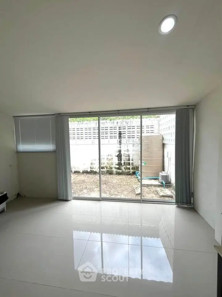 Spacious living room with large windows and garden view, perfect for natural light lovers.