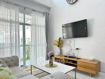 Modern living room with stylish decor, wall-mounted TV, and large windows for natural light.