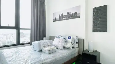 Modern bedroom with city view, stylish decor, and comfortable bedding in a high-rise apartment.
